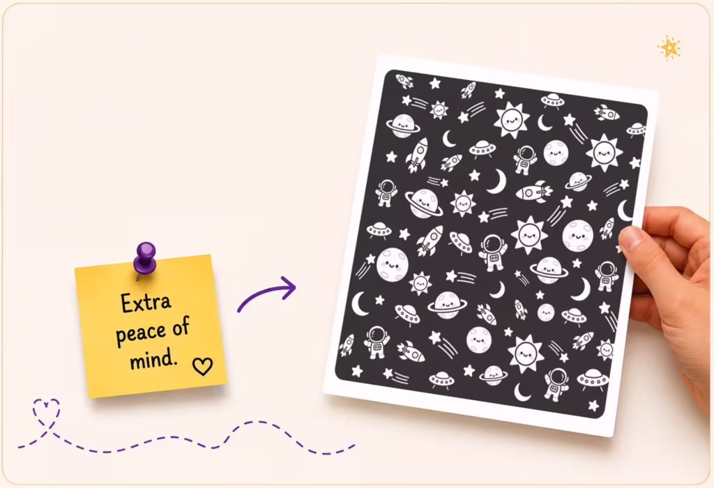 A hand holding a black protective sheet with outer space illustrations, designed to sit behind coloring pages to block marker bleed.